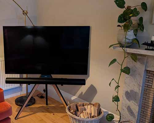 corner TV stand by the fireplace, maple wood finish, with 65-inch TV