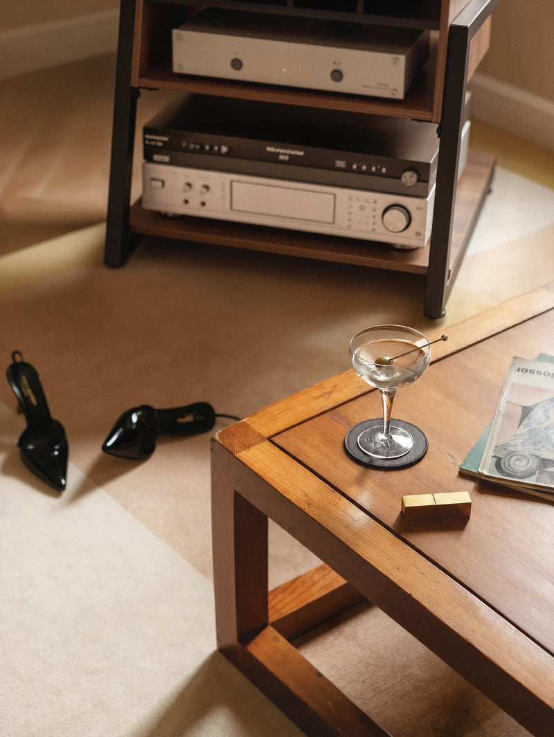 Close-up of hi-fi equipment on the lower shelves of the FITUEYES Eiffel RS05 beside a wooden coffee table