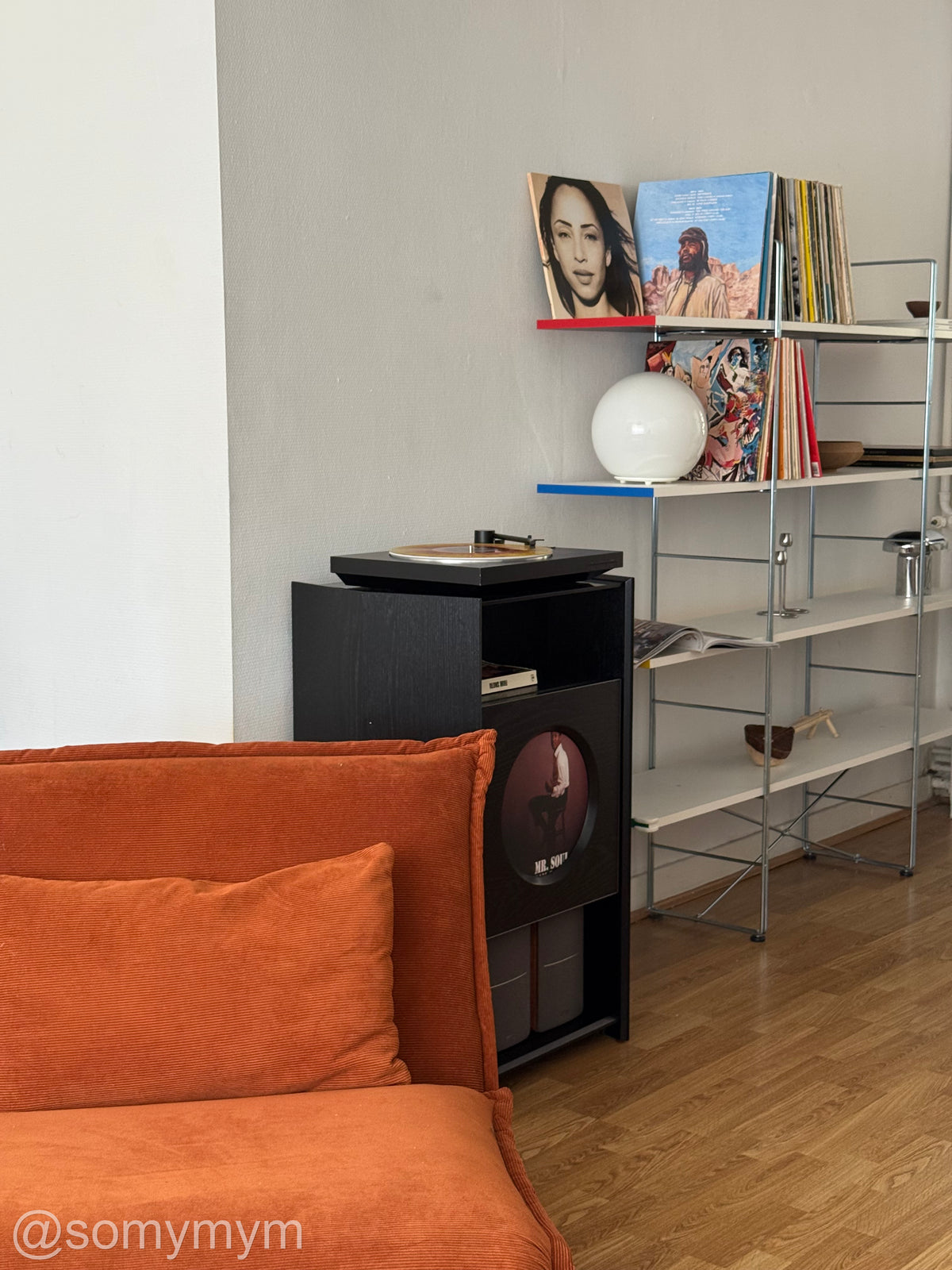 A record stand behind an orange lounge chair